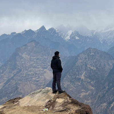Shivam, standing on a cliff facing the Himalayas.
